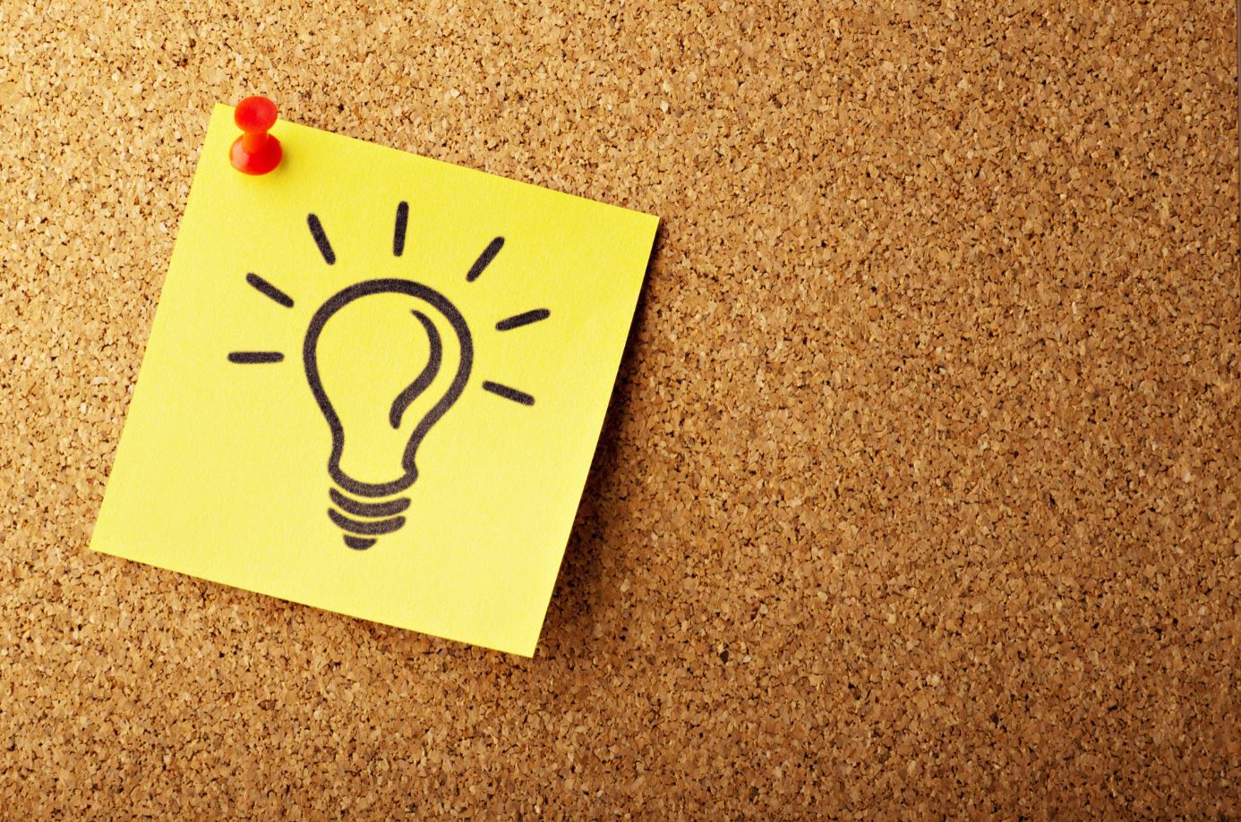 A picture of a yellow post it note with a lightbulb picture on it on a cork notice board